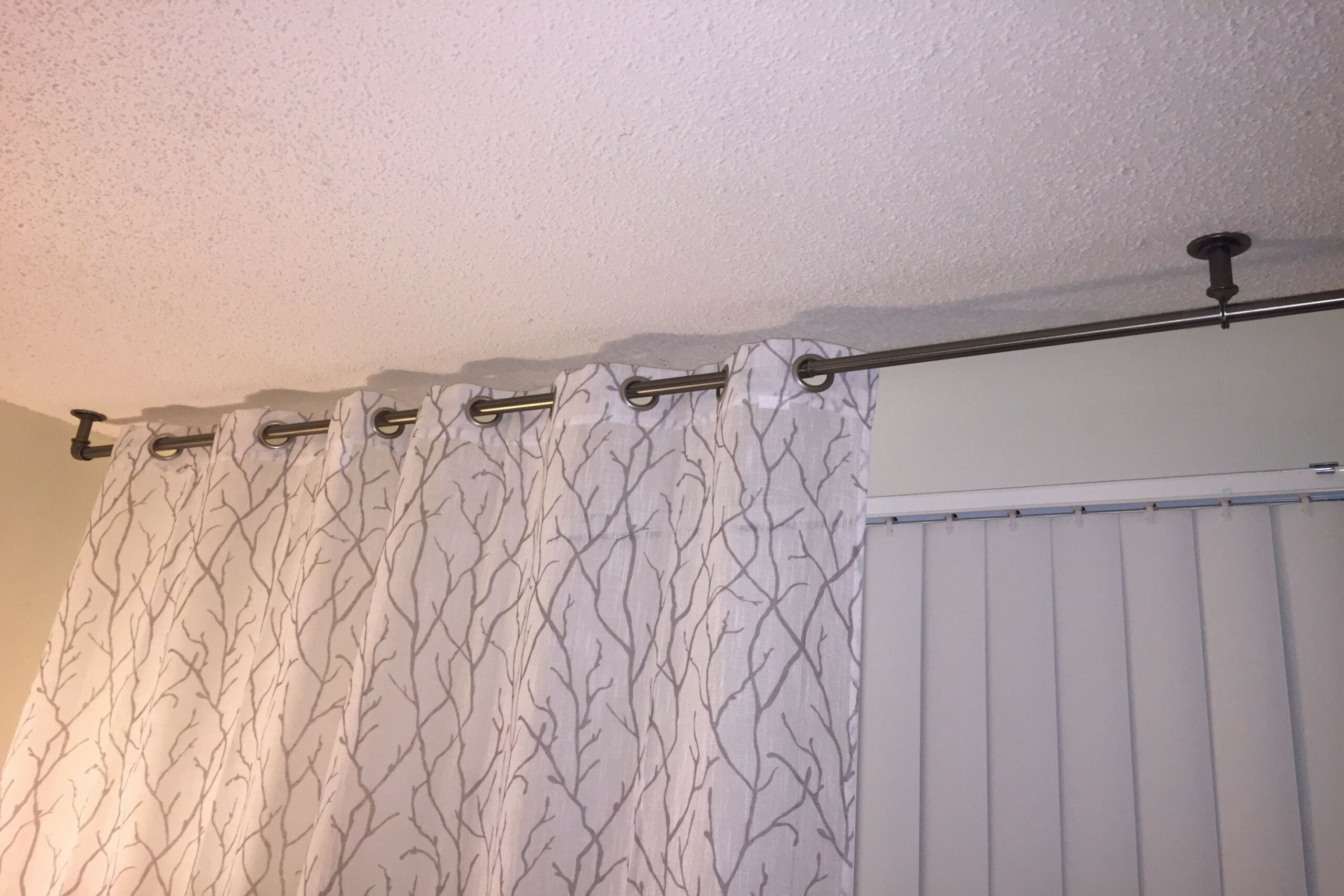 Need drapes to hang over vertical blinds? Mount rod to ceiling